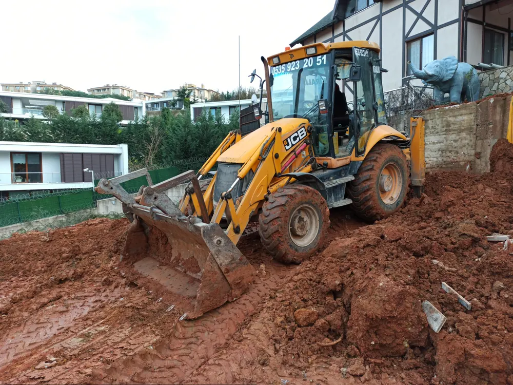 Balçıklı zeminde çalışan JCB kazıcı-yükleyici