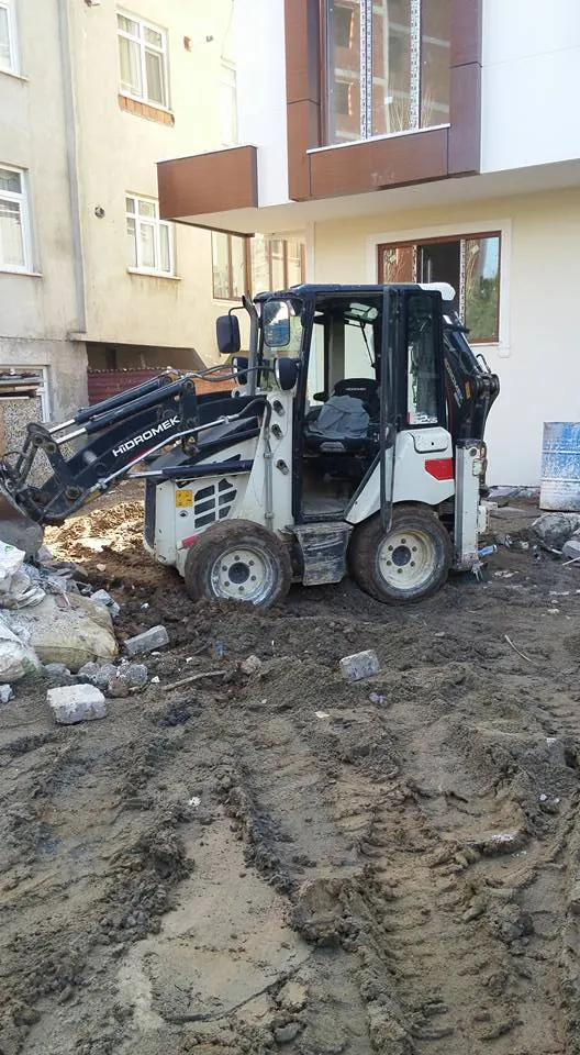 Apartman önünde çalışan kompakt kazıcı-yükleyici